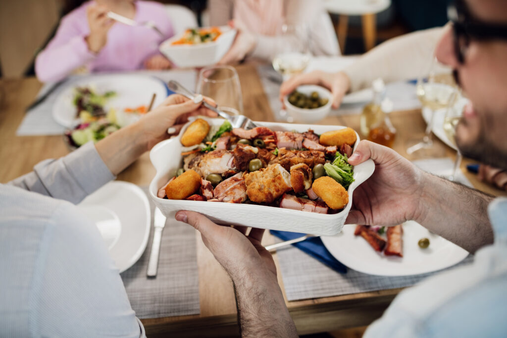 Close-up of couple passing food to each other while having lunch with their family.